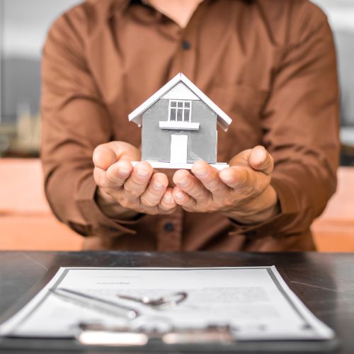 man holding house with mortgage application on the table